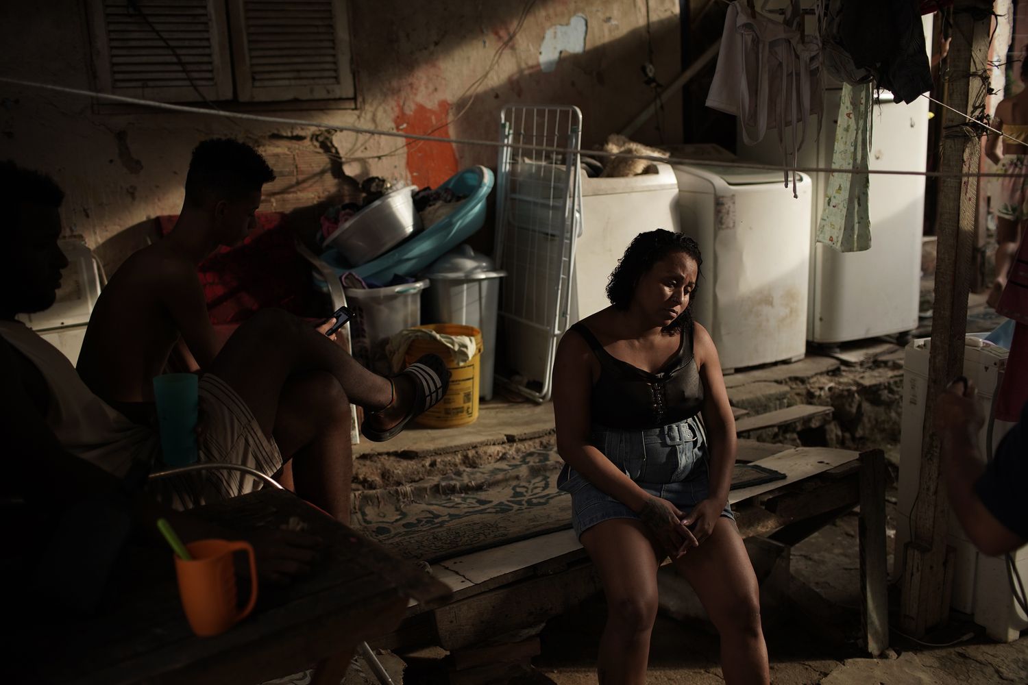 Mulher sentada ao lado dos filhos, no quintal de sua casa na favela do Turano, no Rio de Janeiro